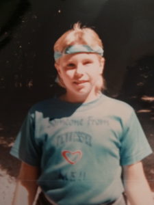 a young white girl has a bandana tied around her head a tight t-shirt in an old photograph from the 1980s